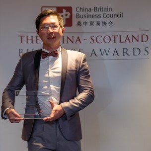 A man in a suit holds a glass award trophy