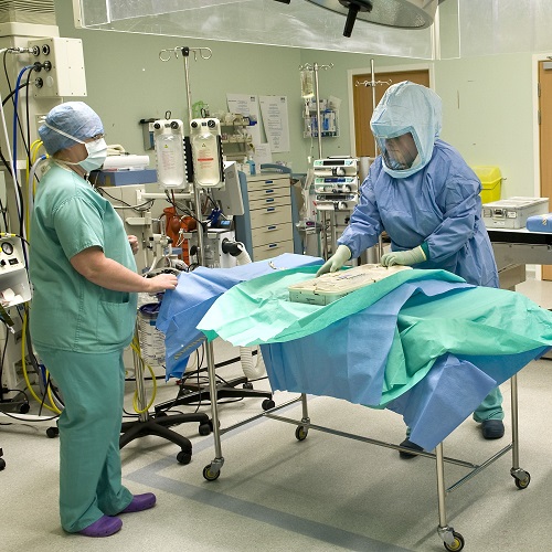 Two health professionals in scrubs and masks in operating theatre