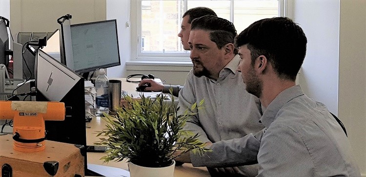 Two men talking in front of a computer in an office