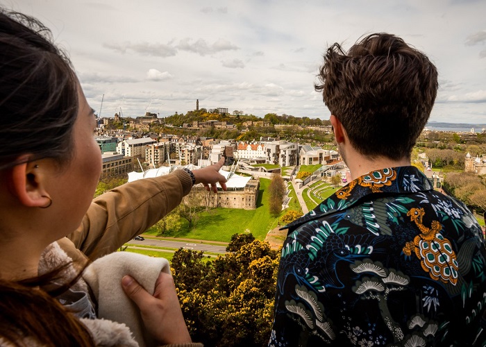 Two tourists up a hill pointing at our Dynamic Earth building 